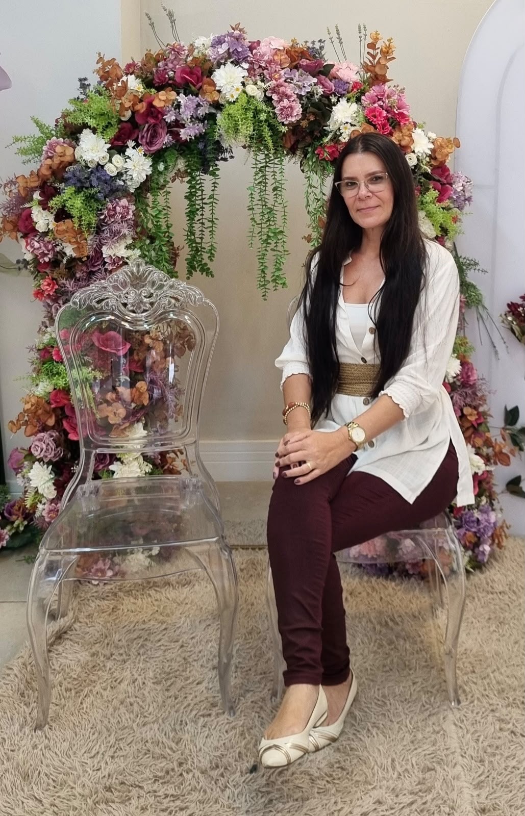 Gilmara Ferreira sentada em um ambiente com flores