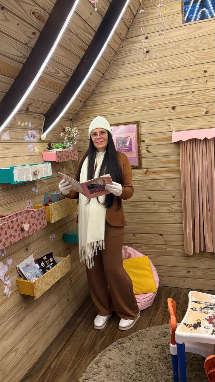 Gilmara Ferreira com um livro em um ambiente de madeira